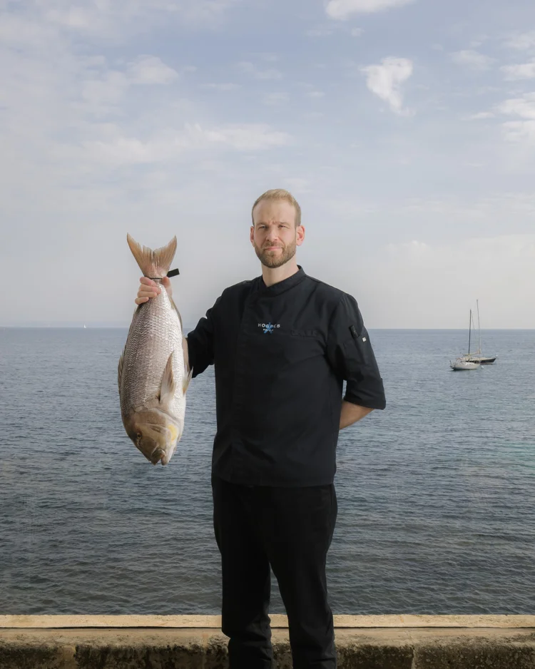Chef sosteniendo un pez junto al mar