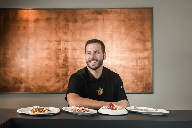 Chef sonriente frente a platos gourmet